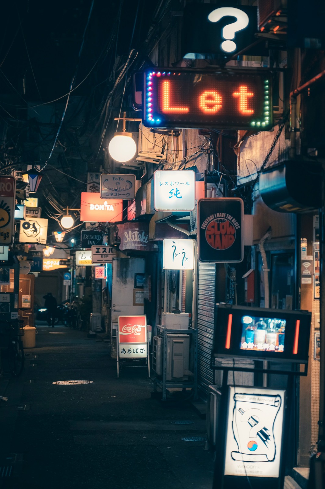 A dark alley crowded with neon signs